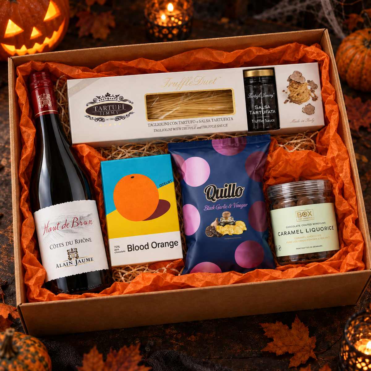 Blodrød Aften halloween-gavekasse med rødvin, trøffelpasta, chokolade, lakrids og chips i orange silkepapir